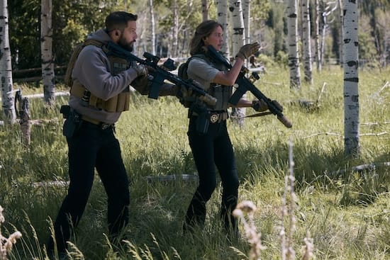 Logan Marshall-Green as Pete Calvin and Arielle Kebbel as Belle Pearson armed in an aspen forest in Marshals Season 2 Episode 3